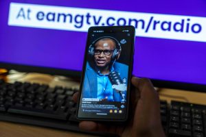 A person watching a vertical TikTok video featuring EAMG Radio content on a smartphone screen