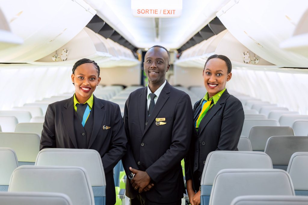 A RwandAir flight attendant delivers the airline's signature warm African hospitality, recognized globally for exceptional cabin service.
